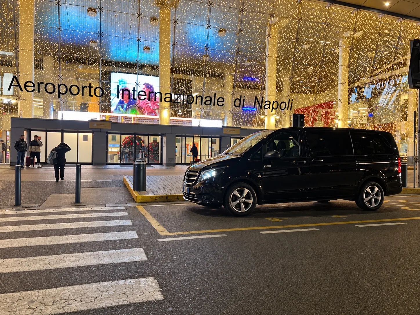 Il Mercedes Vito nero di Casale Transfer Car Service davanti all'Aeroporto Internazionale di Napoli, di sera